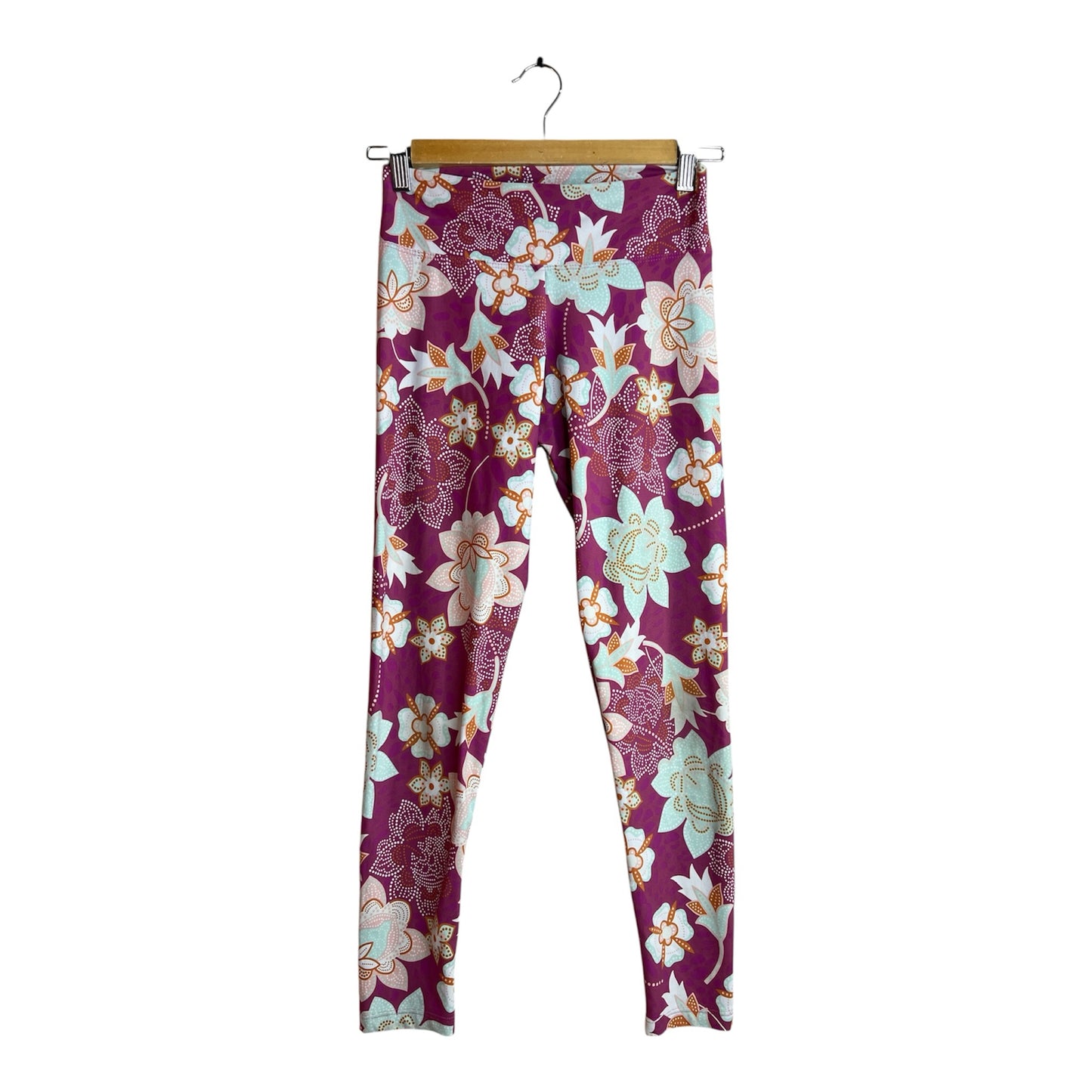 Calzas deportivas La Pichilemina de tiro alto con estampado floral en tonos burdeos, menta y naranja sobre fondo oscuro.