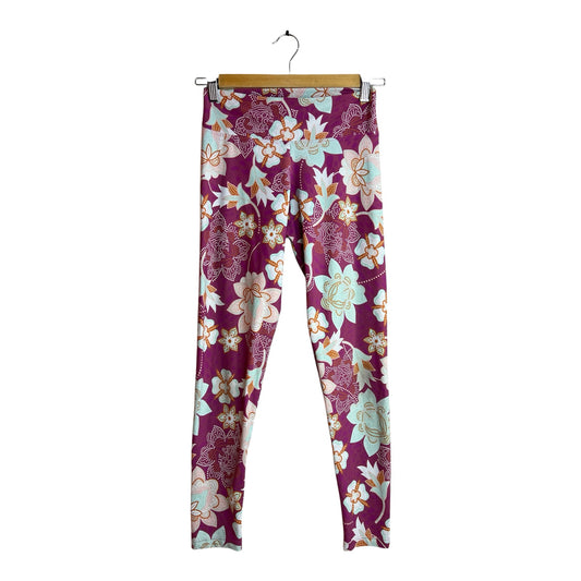 Calzas deportivas La Pichilemina de tiro alto con estampado floral en tonos burdeos, menta y naranja sobre fondo oscuro.