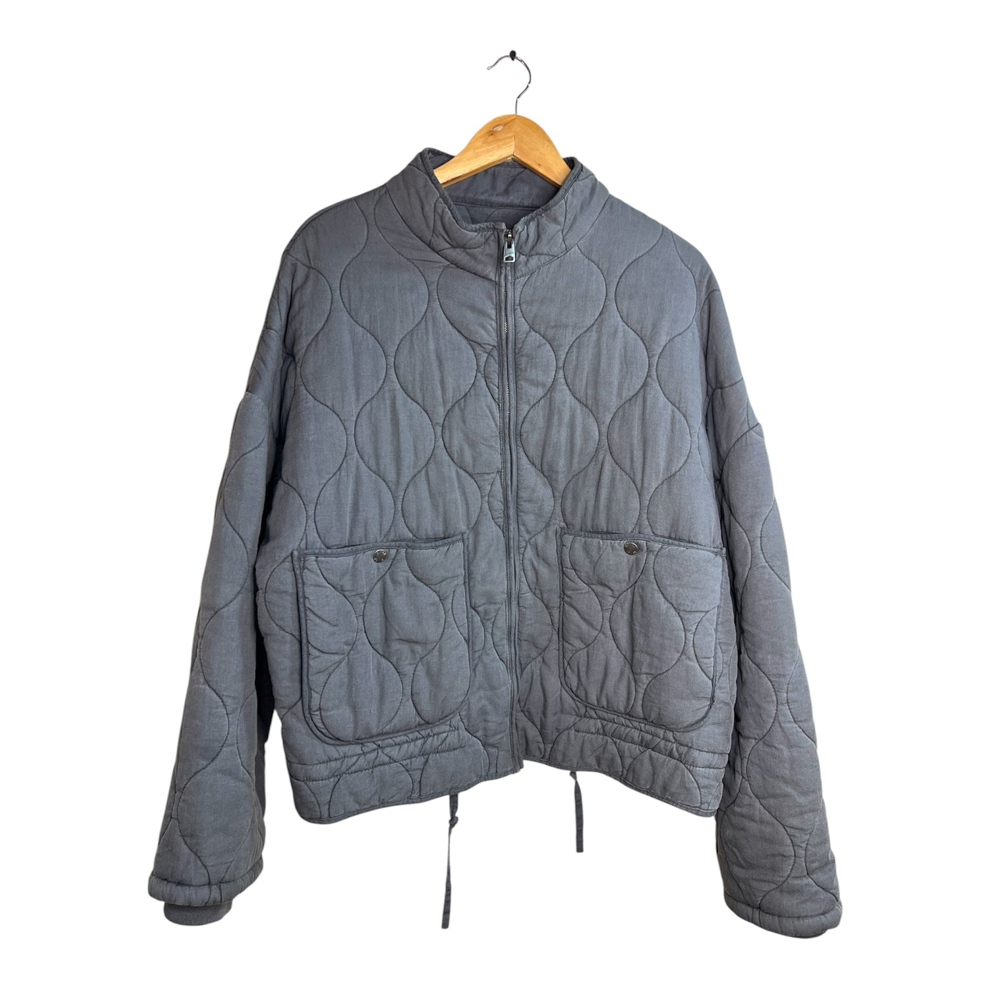 Chaqueta acolchada La Pichilemina gris oscuro con cierre frontal, bolsillos laterales y cordón ajustable en la base.
