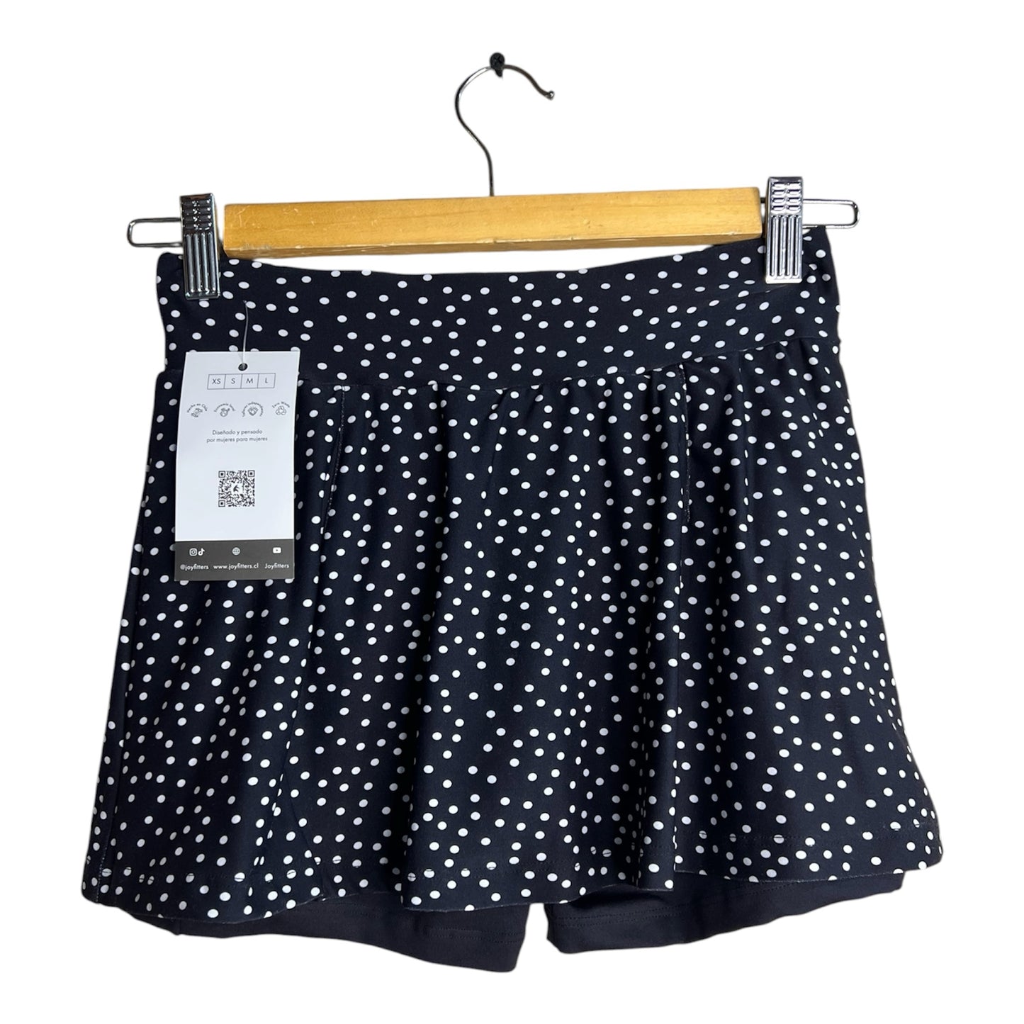 Falda short deportiva La Pichilemina negra con estampado de puntos blancos, diseño fluido y cómodo para entrenamiento.