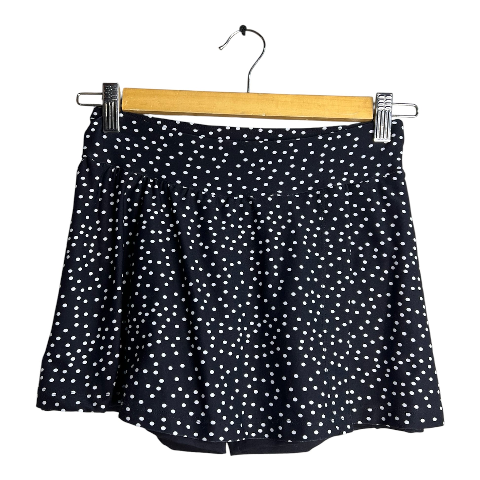 Falda short deportiva La Pichilemina negra con estampado de puntos blancos, diseño fluido y cómodo para ejercicio.